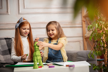 Image showing Two little children, girls together in creativity of the house. Happy kids make handmade toys for games or New Year celebration