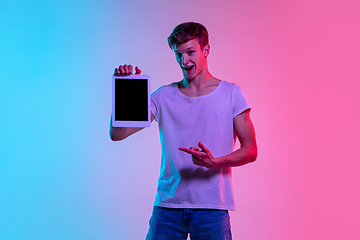 Image showing Young caucasian man\'s portrait on gradient blue-pink studio background in neon light