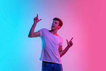 Image showing Young caucasian man\'s portrait on gradient blue-pink studio background in neon light