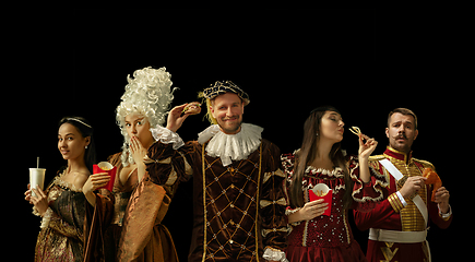 Image showing Medieval people as a royalty persons in vintage clothing on dark background. Concept of comparison of eras, modernity and renaissance. Creative collage.