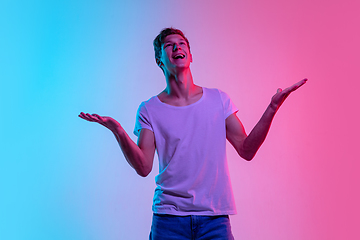 Image showing Young caucasian man\'s portrait on gradient blue-pink studio background in neon light