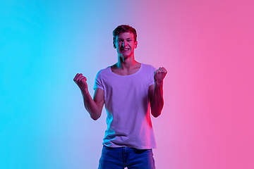 Image showing Young caucasian man\'s portrait on gradient blue-pink studio background in neon light