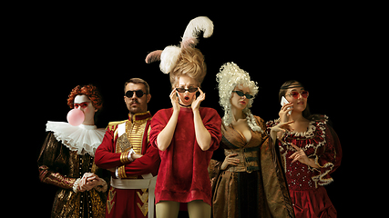 Image showing Medieval people as a royalty persons in vintage clothing on dark background. Concept of comparison of eras, modernity and renaissance. Creative collage.