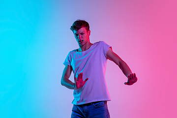 Image showing Young caucasian man\'s portrait on gradient blue-pink studio background in neon light