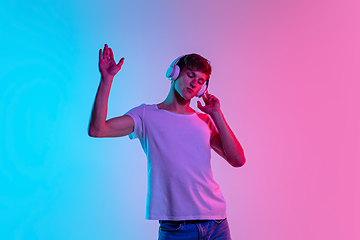 Image showing Young caucasian man\'s portrait on gradient blue-pink studio background in neon light