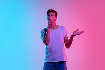 Image showing Young caucasian man\'s portrait on gradient blue-pink studio background in neon light