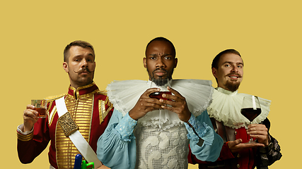 Image showing Medieval men as a royalty persons in vintage clothing on yellow background. Concept of comparison of eras, modernity and renaissance. Creative collage.