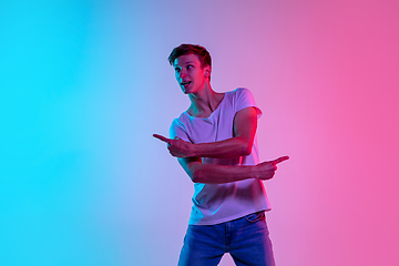 Image showing Young caucasian man\'s portrait on gradient blue-pink studio background in neon light