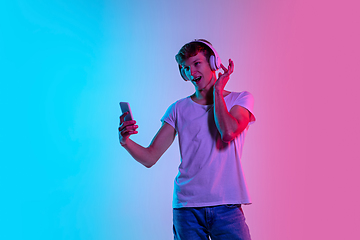 Image showing Young caucasian man\'s portrait on gradient blue-pink studio background in neon light