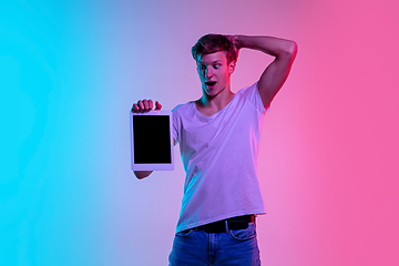 Image showing Young caucasian man\'s portrait on gradient blue-pink studio background in neon light