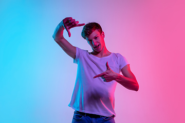 Image showing Young caucasian man\'s portrait on gradient blue-pink studio background in neon light