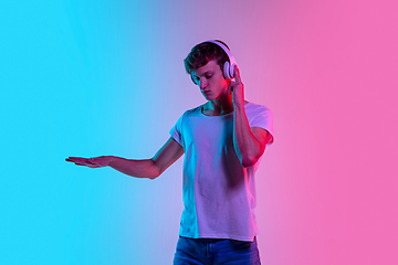 Image showing Young caucasian man\'s portrait on gradient blue-pink studio background in neon light