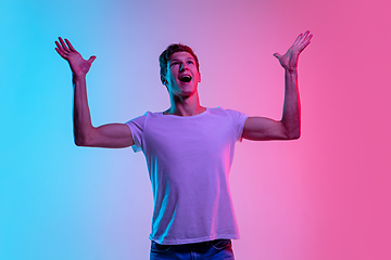 Image showing Young caucasian man\'s portrait on gradient blue-pink studio background in neon light