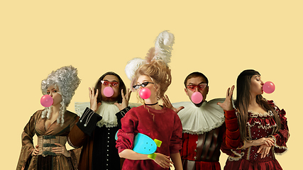Image showing Medieval people as a royalty persons in vintage clothing on yellow background. Concept of comparison of eras, modernity and renaissance. Creative collage.