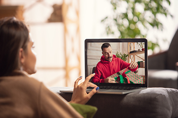 Image showing Celebration and holidays during quarantine concept. Friends or family unpacking gifts while talking using video call