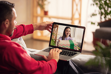 Image showing Celebration and holidays during quarantine concept. Friends or family unpacking gifts while talking using video call