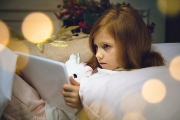 Image showing Happy caucasian little girl during video call or messaging with Santa using laptop and home devices, looks delighted and happy