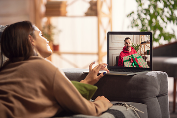 Image showing Celebration and holidays during quarantine concept. Friends or family unpacking gifts while talking using video call