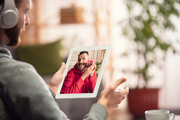 Image showing Celebration and holidays during quarantine concept. Friends or family unpacking gifts while talking using video call