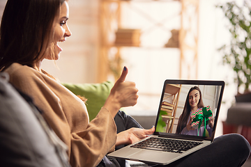 Image showing Celebration and holidays during quarantine concept. Friends or family unpacking gifts while talking using video call