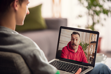 Image showing Celebration and holidays during quarantine concept. Friends or family unpacking gifts while talking using video call