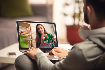 Image showing Celebration and holidays during quarantine concept. Friends or family unpacking gifts while talking using video call