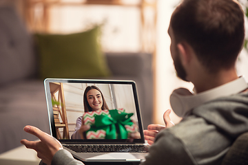 Image showing Celebration and holidays during quarantine concept. Friends or family unpacking gifts while talking using video call