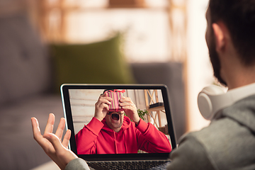 Image showing Celebration and holidays during quarantine concept. Friends or family unpacking gifts while talking using video call