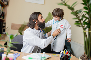 Image showing Paediatrician doctor examining a child in comfortabe medical office