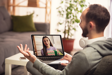 Image showing Celebration and holidays during quarantine concept. Friends or family unpacking gifts while talking using video call