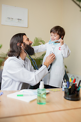 Image showing Paediatrician doctor examining a child in comfortabe medical office