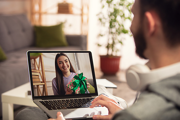 Image showing Celebration and holidays during quarantine concept. Friends or family unpacking gifts while talking using video call