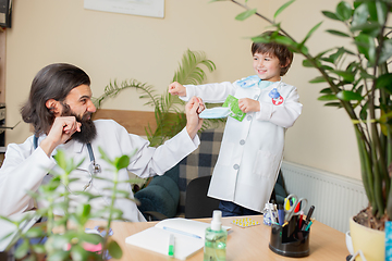 Image showing Paediatrician doctor examining a child in comfortabe medical office