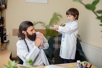 Image showing Paediatrician doctor examining a child in comfortabe medical office