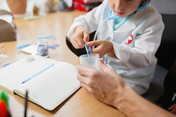 Image showing Little boy playing pretends like doctor examining a man in comfortabe medical office