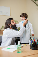 Image showing Paediatrician doctor examining a child in comfortabe medical office