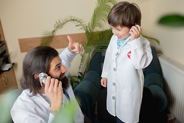 Image showing Paediatrician doctor examining a child in comfortabe medical office