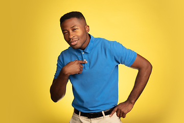 Image showing Young african-american man\'s portrait isolated on yellow studio background, facial expression. Beautiful male half-lenght portrait with copyspace.