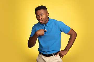 Image showing Young african-american man\'s portrait isolated on yellow studio background, facial expression. Beautiful male half-lenght portrait with copyspace.