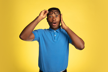 Image showing Young african-american man\'s portrait isolated on yellow studio background, facial expression. Beautiful male half-lenght portrait with copyspace.