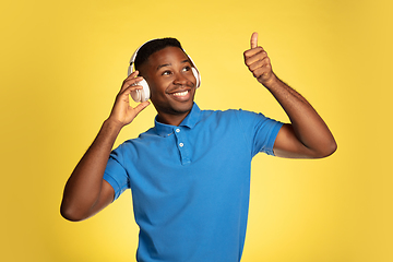 Image showing Young african-american man\'s portrait isolated on yellow studio background, facial expression. Beautiful male half-lenght portrait with copyspace.