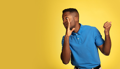 Image showing Young african-american man\'s portrait isolated on yellow studio background, facial expression. Beautiful male half-lenght portrait with copyspace.