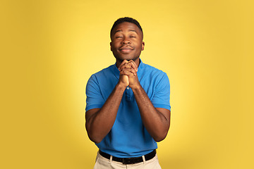 Image showing Young african-american man\'s portrait isolated on yellow studio background, facial expression. Beautiful male half-lenght portrait with copyspace.