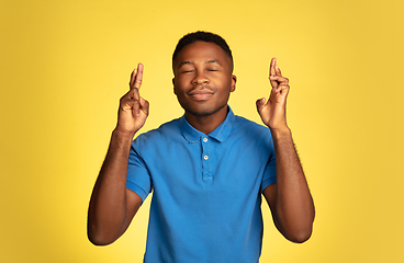 Image showing Young african-american man\'s portrait isolated on yellow studio background, facial expression. Beautiful male half-lenght portrait with copyspace.