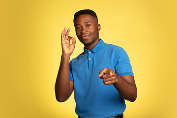 Image showing Young african-american man\'s portrait isolated on yellow studio background, facial expression. Beautiful male half-lenght portrait with copyspace.