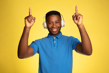 Image showing Young african-american man\'s portrait isolated on yellow studio background, facial expression. Beautiful male half-lenght portrait with copyspace.