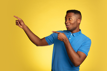 Image showing Young african-american man\'s portrait isolated on yellow studio background, facial expression. Beautiful male half-lenght portrait with copyspace.