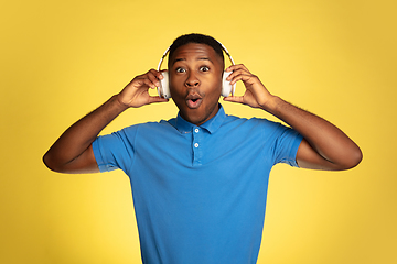 Image showing Young african-american man\'s portrait isolated on yellow studio background, facial expression. Beautiful male half-lenght portrait with copyspace.