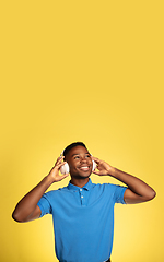 Image showing Young african-american man\'s portrait isolated on yellow studio background, facial expression. Beautiful male half-lenght portrait with copyspace.