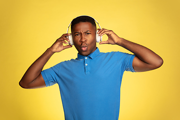 Image showing Young african-american man\'s portrait isolated on yellow studio background, facial expression. Beautiful male half-lenght portrait with copyspace.